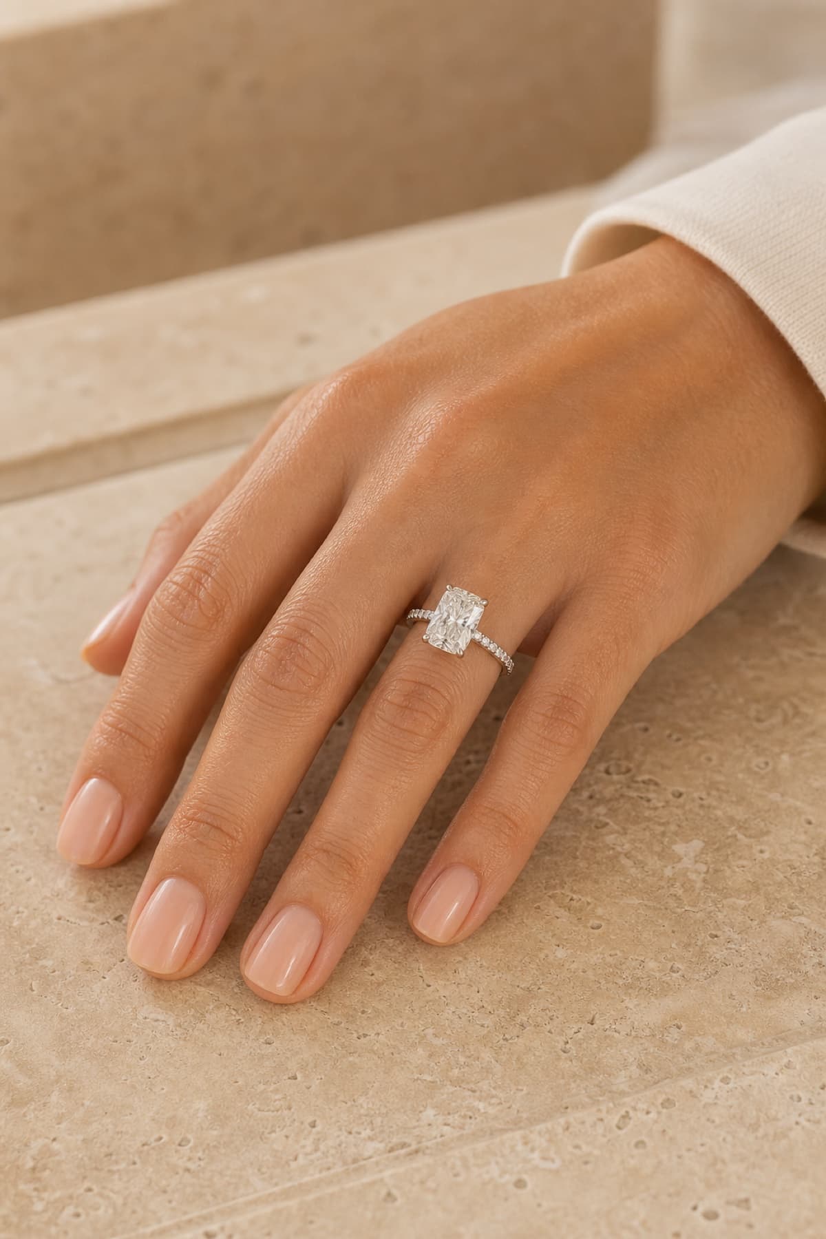 Radiant hidden halo engagement ring on a woman's left hand ring finger in a clean studio close-up